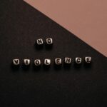 Artistic composition with text cubes spelling 'No Violence' on a two-tone background.